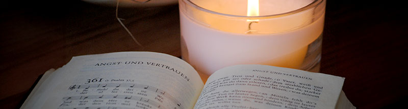 Offenes Gesangbuch vor einer brennenden Kerze