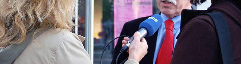 Reporterin hält ein Mikrofon zum Interviewpartner